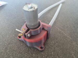 Det er en 3D printet peristaltisk pumpe. Det eneste i den som ikke er 3D printet er kugle leje, så den kører bedre, en motor, en skrue til at holde motoren på plads og en "FDA-Food grade" silikone slange, så den kan fint blive brugt til væsker der skal drikkes. Den er 100% funktionel og kan skilles uden brug af værktøj. Pumpen er resultatet af et projekt som studerende. Selve pumpen er ca. 75x60x30mm, så den har en dejlig og behagelig størrelse i ens hånd.