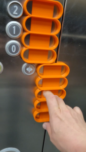 En "fingertrappe" til en elev, der har muskelsvind, og ikke har styrke i armene til at trykke på knapperne i elevatoren. Med "fingertrappen" kan han være mere selvhjulpen og uafhængig af personale.