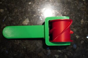 Dette projekt er et 3D-printet køkkenredskab designet til at gøre det nemt at lave ensartede klejner. Rullen køres hen over dejen og skærer automatisk de karakteristiske diagonale former, så alle klejner får samme størrelse og form hver gang. Designet består af tre 3D-printede dele: et ergonomisk håndtag, en skrue som holder delene sammen, og selve udskærerhovedet med rullehjul. Konstruktionen gør værktøjet enkelt, robust og let at samle uden andre komponenter. Projektet viser, hvordan 3D-print kan bruges til at skabe praktiske og funktionelle redskaber til køkkenet. Ved at designe og printe alle dele selv kan værktøjet nemt tilpasses og produceres, så hjemmebagere kan få et simpelt redskab til perfekte klejner hver gang.